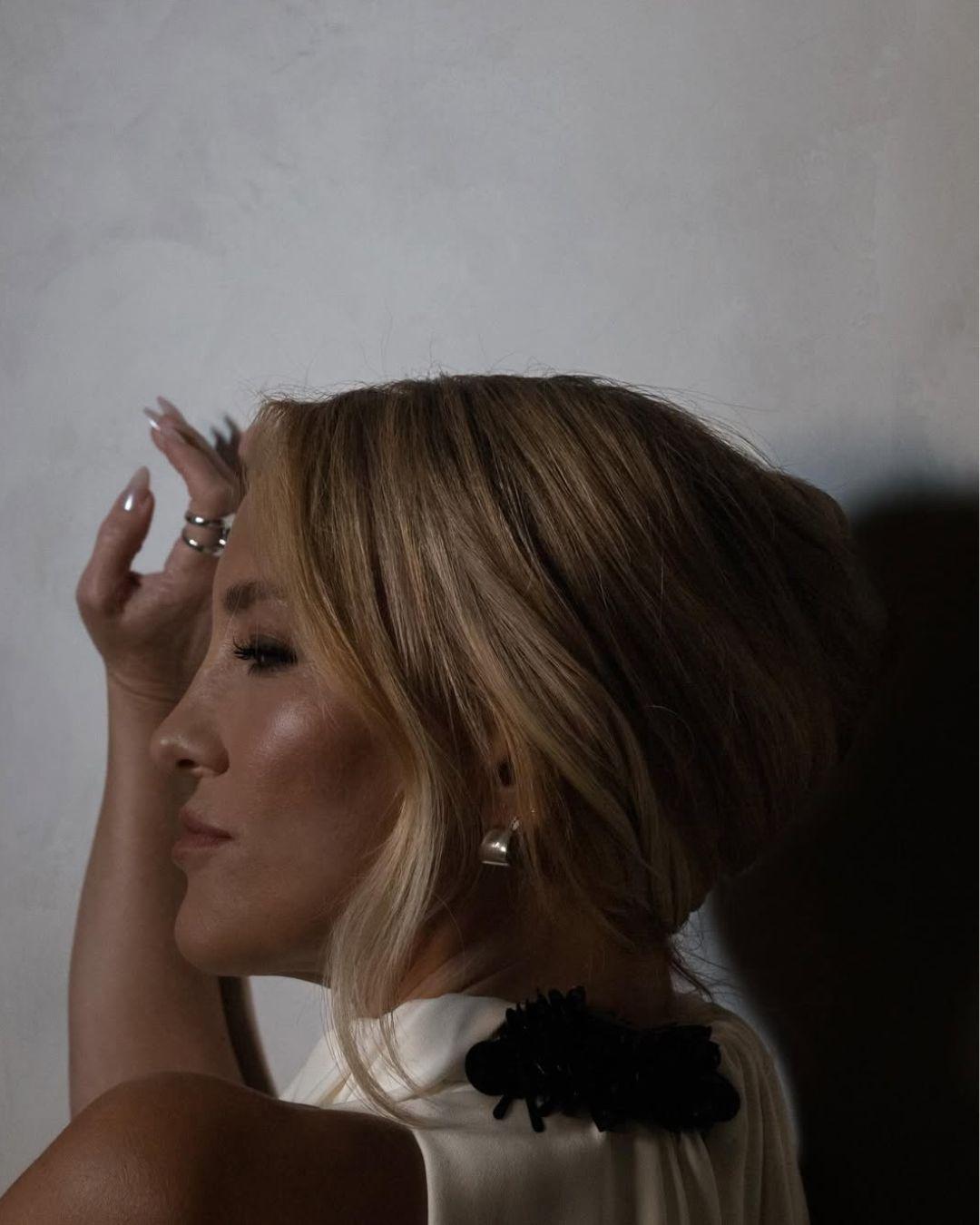 Side view of Kate Hudson’s soft French twist updo with face-framing blonde pieces and glossy finish