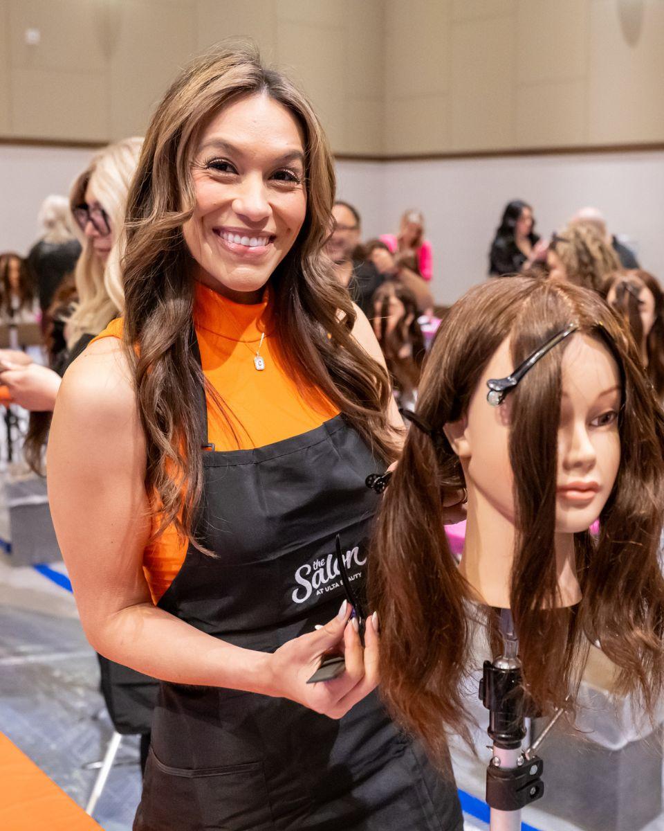 Ulta Beauty stylist smiles while working on a mannequin during hands-on education at Field Leadership Conference