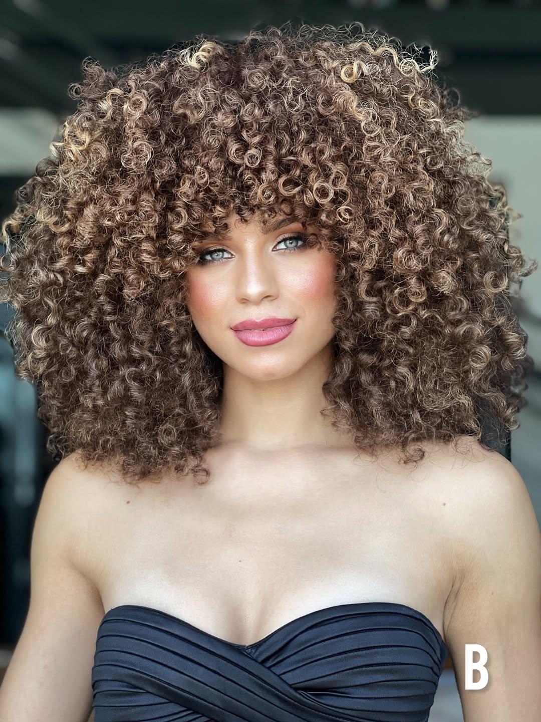 Front view of a curly hair transformation with a mocha brunette base and beige-blonde highlights, creating multidimensional bronde color and defined curls.