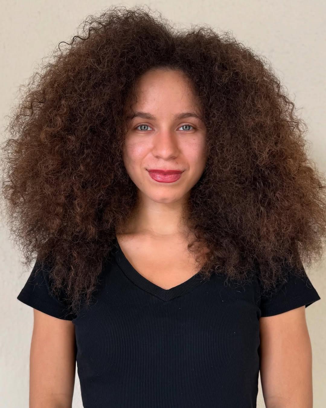 Before photo of long, dark brunette curly hair with natural texture and a single-process color prior to a dimensional bronde highlighting service.