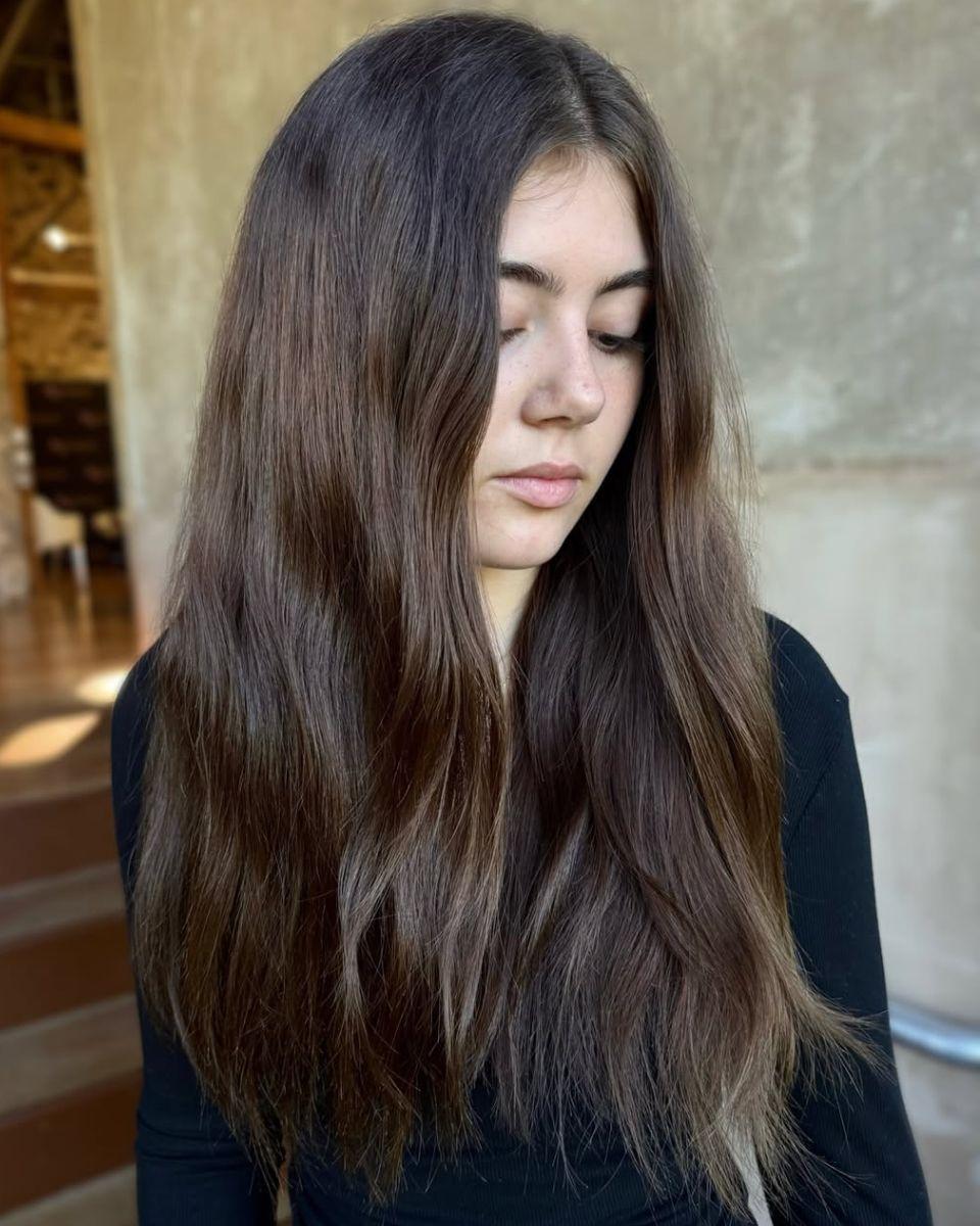 Model with long, natural brunette hair before color service, showcasing a deep brunette base and minimal existing dimension.