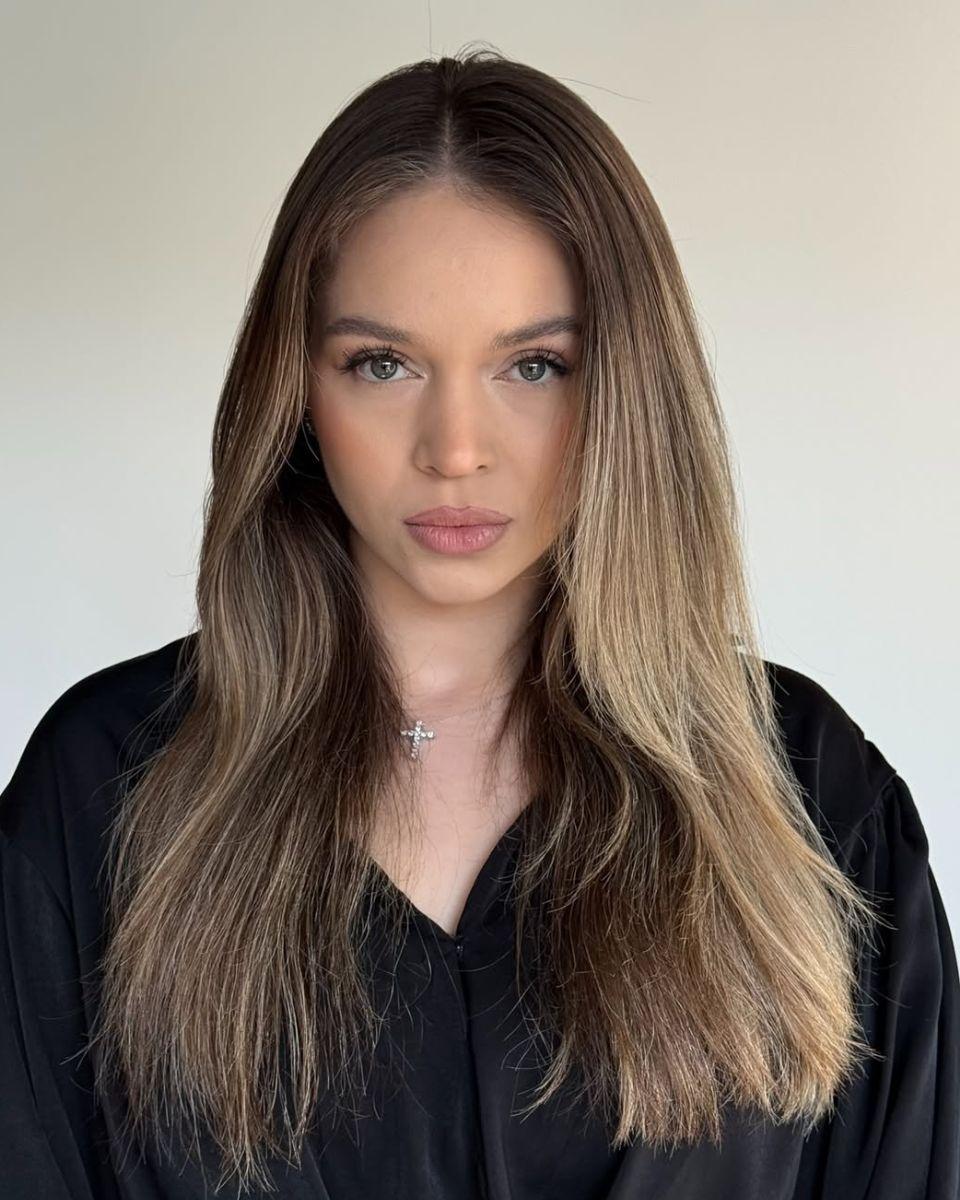 Before photo of grown-out brunette blonde hair with natural depth and subtle warm blonde ends.