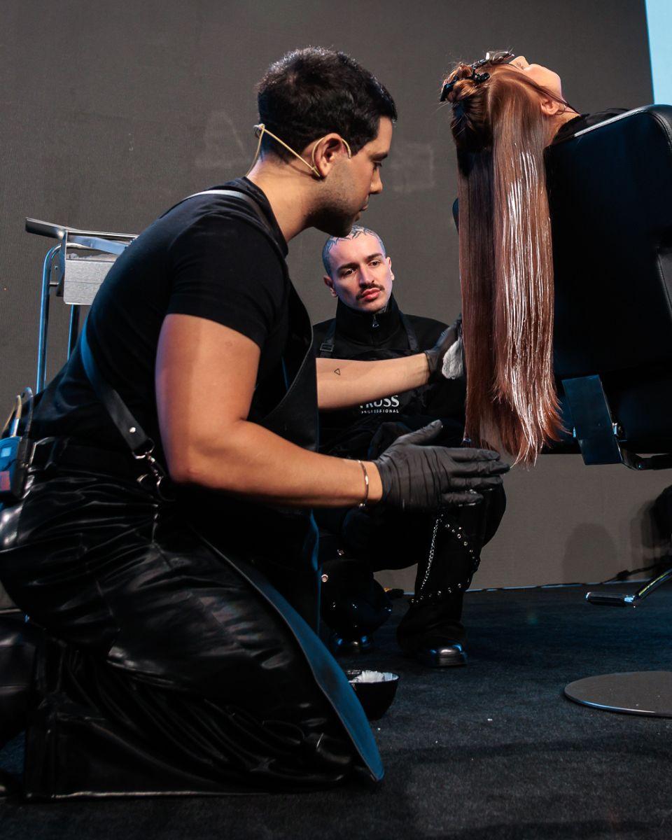 Danilo Herbert works through the front section of a model’s long dimensional blonde hair during a live class at TRUSS Connection Global.