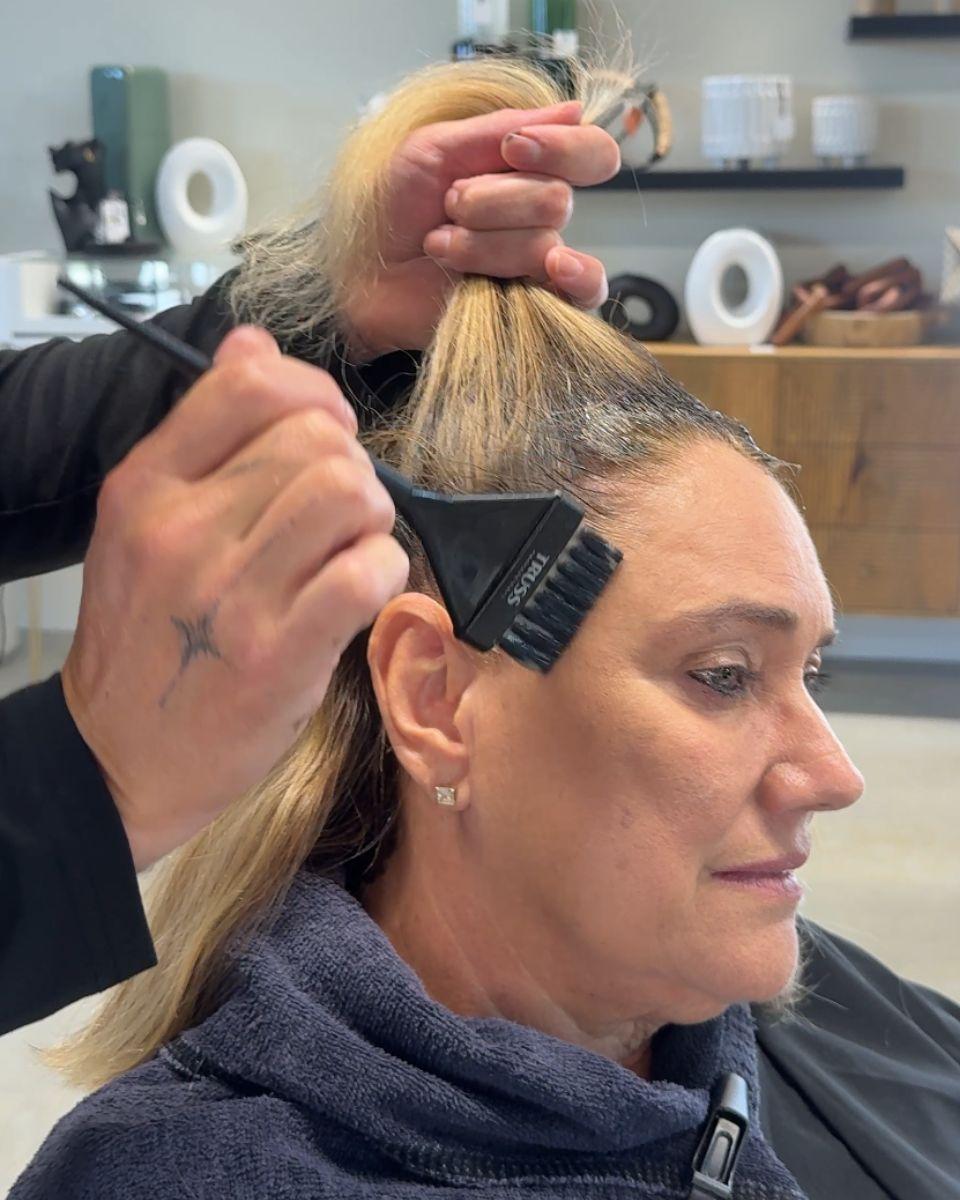 Mickey Colon applies TRUSS Fast Color to a client’s gray regrowth at the front hairline.