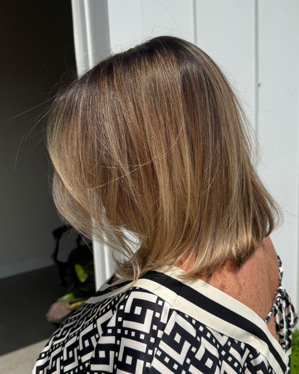 Finished blonde bob with soft dimension, blended gray coverage and a smooth, shiny blowout.