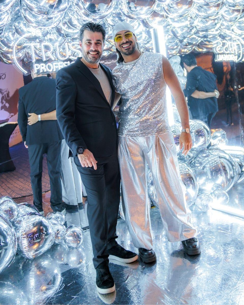 A guest poses with a silver stilt performer in front of a metallic TRUSS Professional party backdrop.