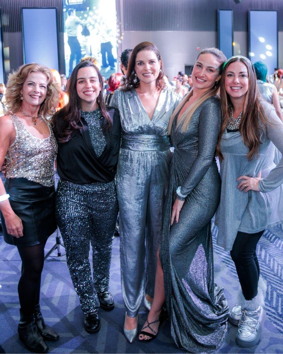A group of guests pose together in silver and metallic outfits during a TRUSS Professional event party.