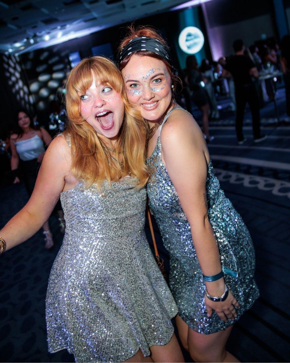 Behindthechair.com Senior Editor Lauren Freas and TRUSS Professional Brand & Marketing Specialist Alessandra Heck pose together in silver outfits during the event’s themed party.