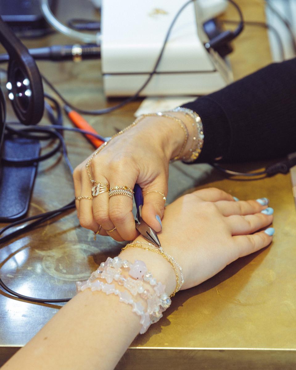 Close-up of a permanent jewelry artist securing a delicate bracelet on a guest’s wrist.