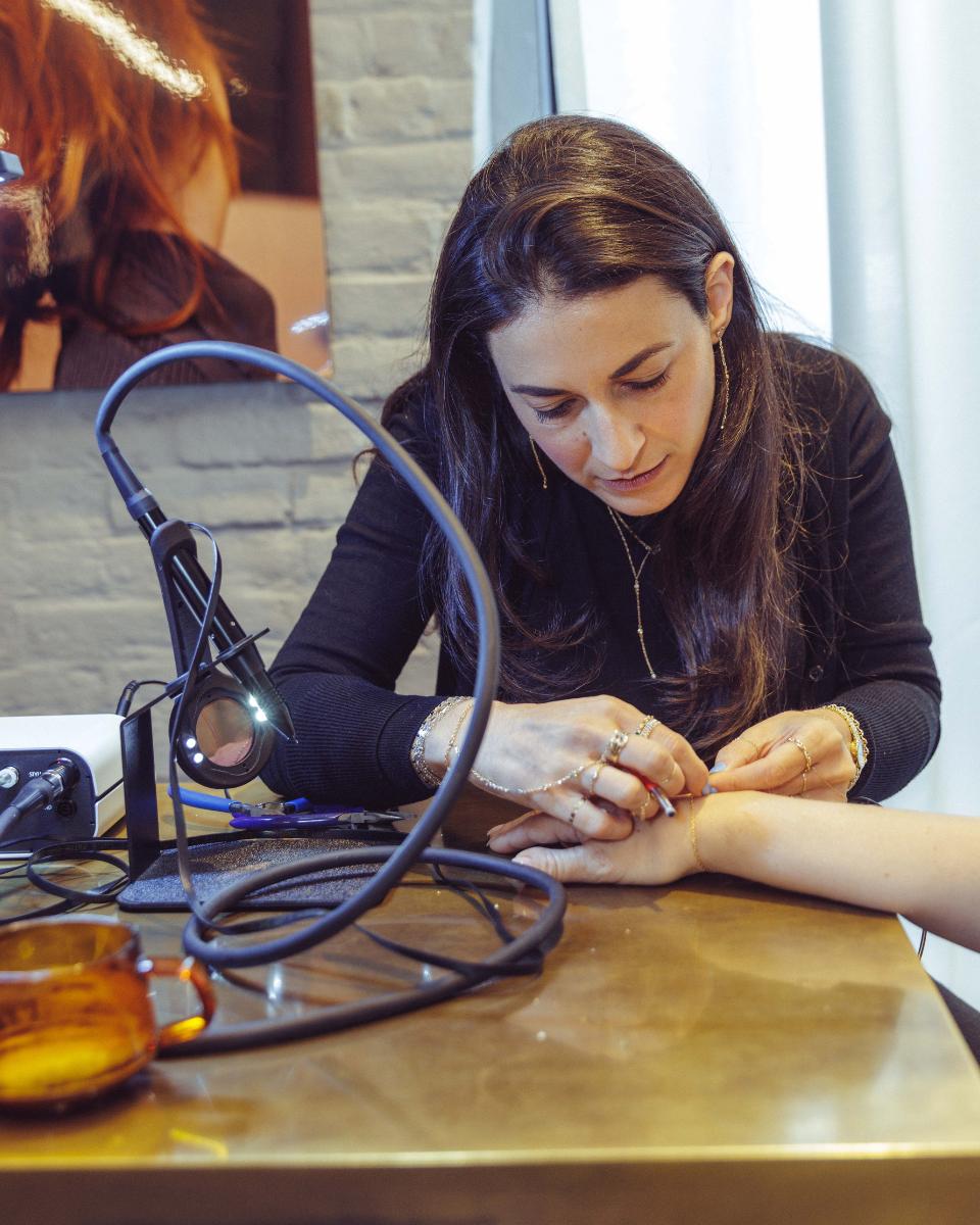 A permanent jewelry artist secures a bracelet on a guest’s wrist during the milk_shake Everlasting Bonds event.