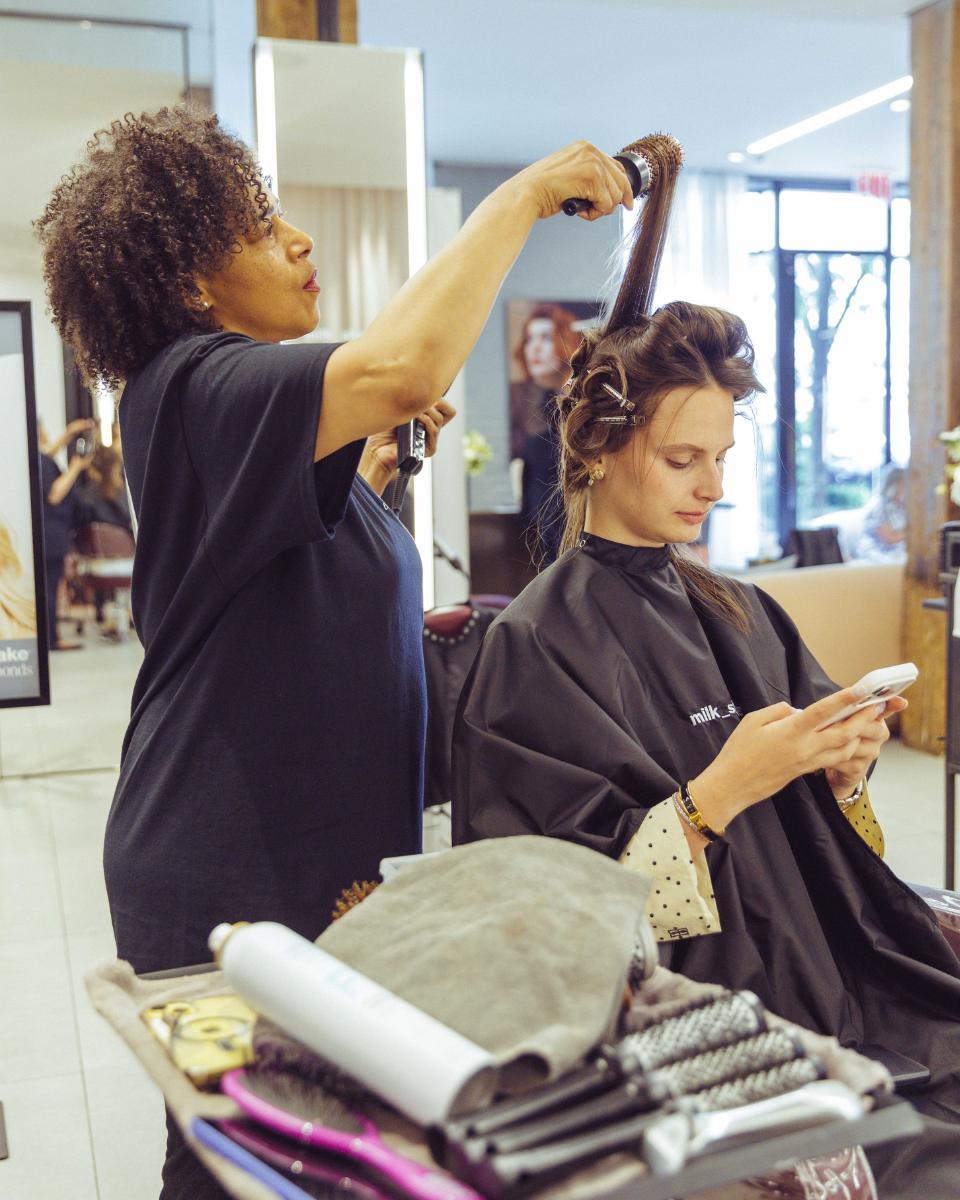 A stylist blow-dries a guest’s hair with a round brush during the milk_shake Everlasting Bonds launch event.