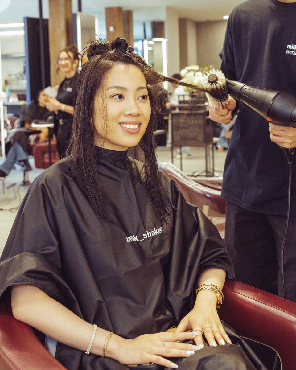A guest smiles while a stylist blow-dries her hair with a round brush during the Everlasting Bonds launch event.