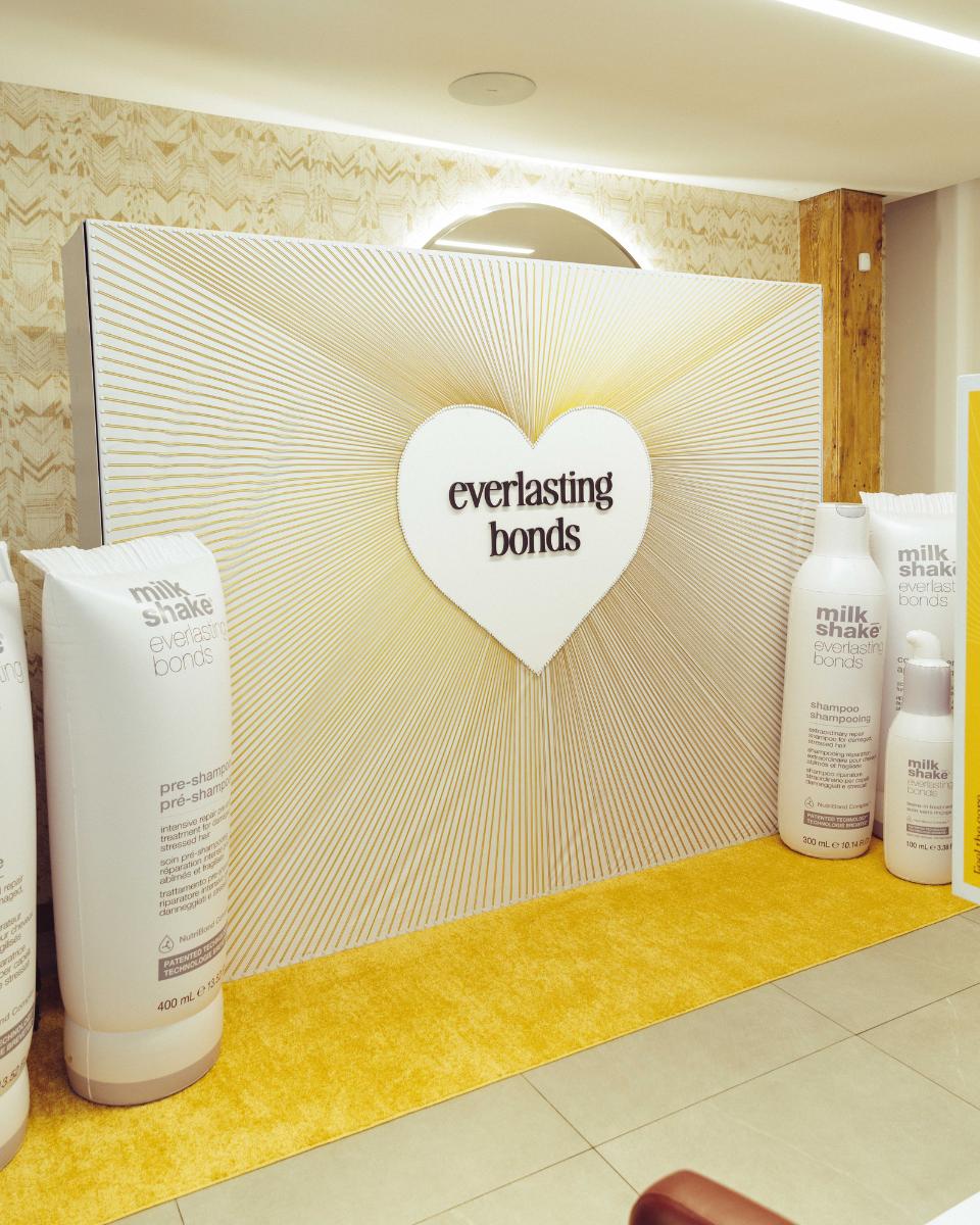 Oversized milk_shake Everlasting Bonds product displays frame a heart-shaped event backdrop with gold detailing.