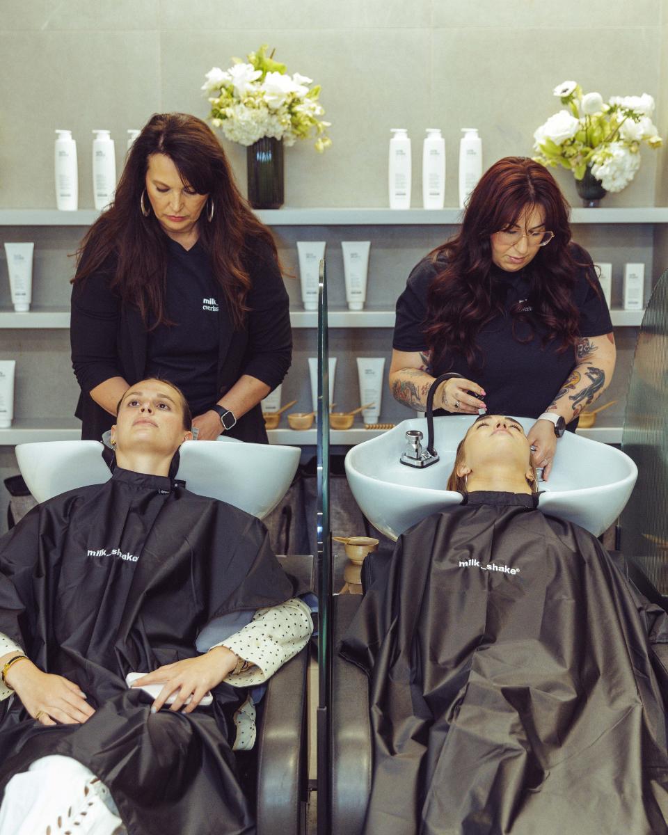 Two guests receive milk_shake Everlasting Bonds treatments at the shampoo bowls during the launch event.