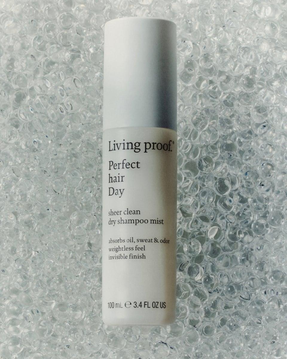 Living Proof Perfect hair Day™ Sheer Clean Dry Shampoo Mist bottle displayed on a clear, bubble-textured surface.