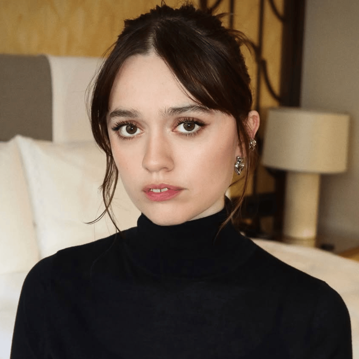 Aimee Lou Wood's glossy brunette updo in a hotel room posing
