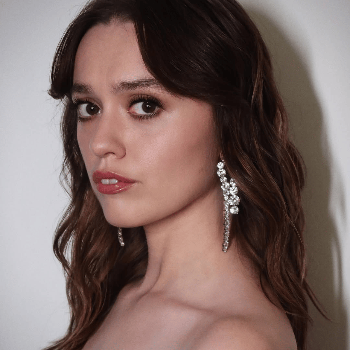 Aimee Lou Wood with soft brunette waves and face-framing layers, styled with a lived-in finish