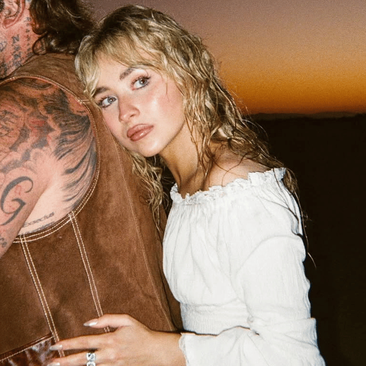 Sabrina Carpenter with tousled buttery blonde waves and curtain bangs at sunset in the “Manchild” music video.