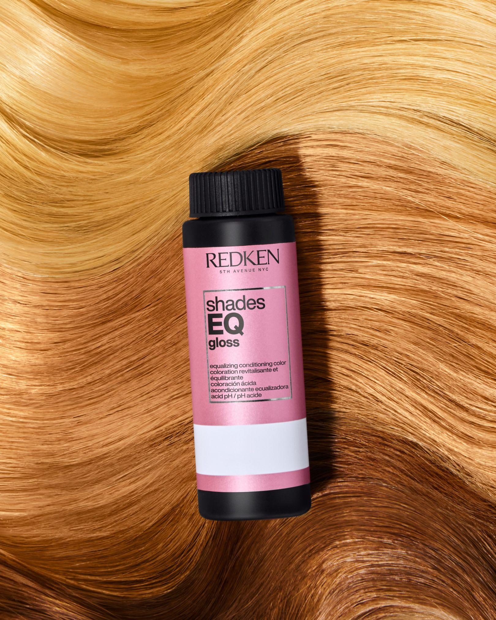 Redken Shades EQ Gloss bottle displayed on warm honey copper hair.