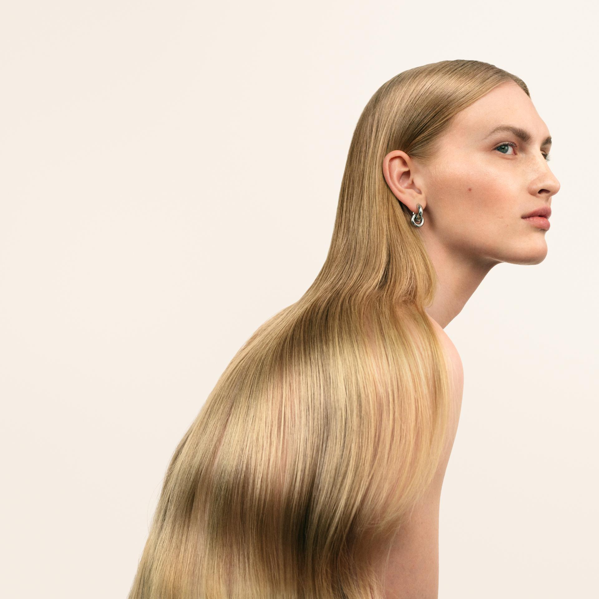 Alt text: Model with long, smooth blonde hair after using Maria Nila Bond Builder, showcasing a sleek, glossy finish.