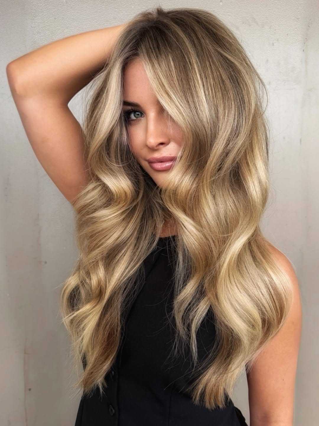 Dimensional blonde balayage with creamy ribbon highlights, a seamless root melt and glamorous cascading waves creating a high-shine finish.
