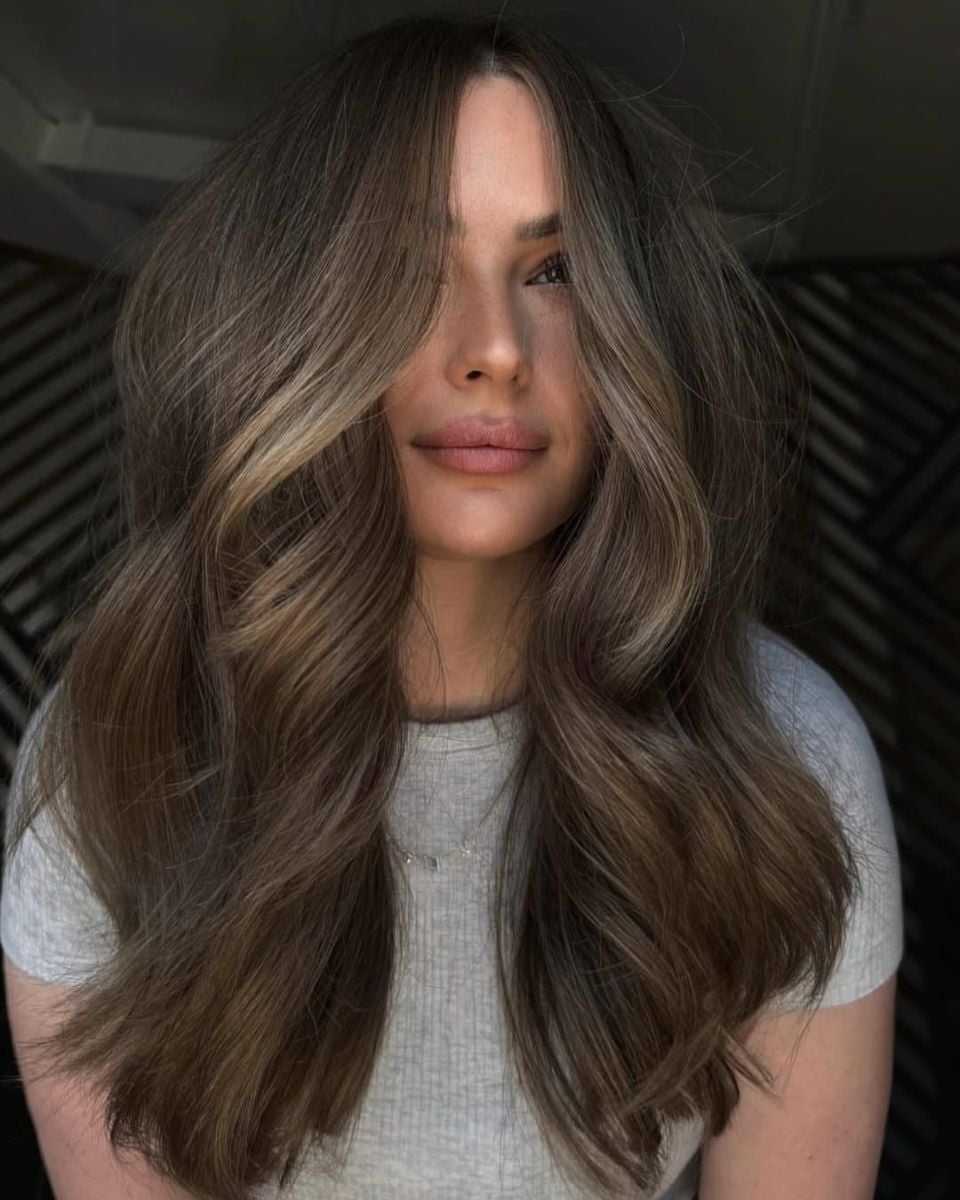 Front view of long lived-in bronde hair with a shadow root, neutral beige highlights and soft voluminous waves.