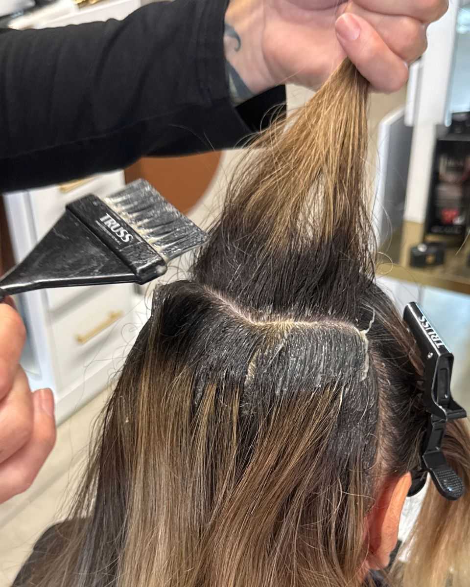Mickey Colon applies TRUSS Fast Color to a curved section of hair during a gray coverage service.