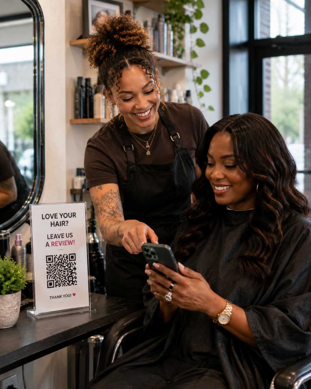 client holding a phone while stylist asks her to leave a review smiling