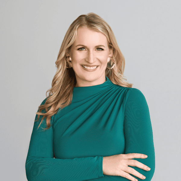 Rachel Jud, CEO of Elevated Beauty Group, smiling confidently in a professional green dress, representing leadership and innovation in the beauty industry.