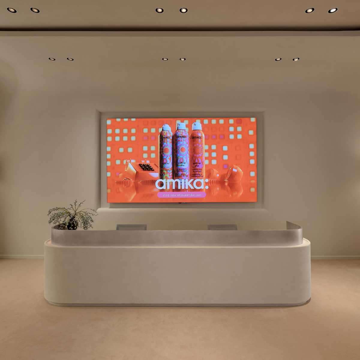 amika’s sleek lobby with a modern reception desk and digital brand display.