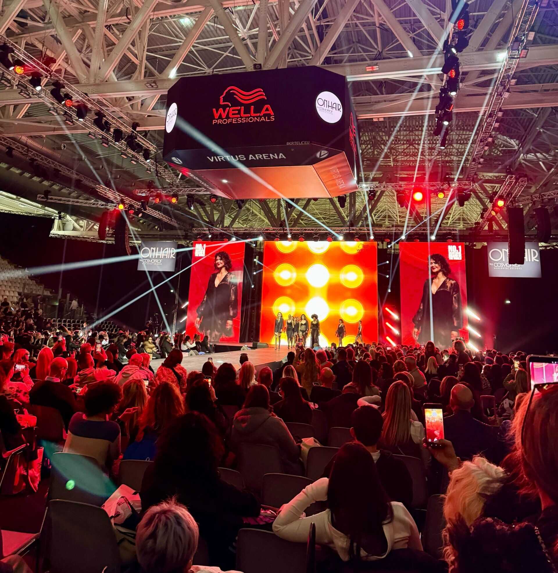 Wella Professionals hair show at Cosmoprof Bologna featuring runway presentation and large digital screens with vibrant lighting
