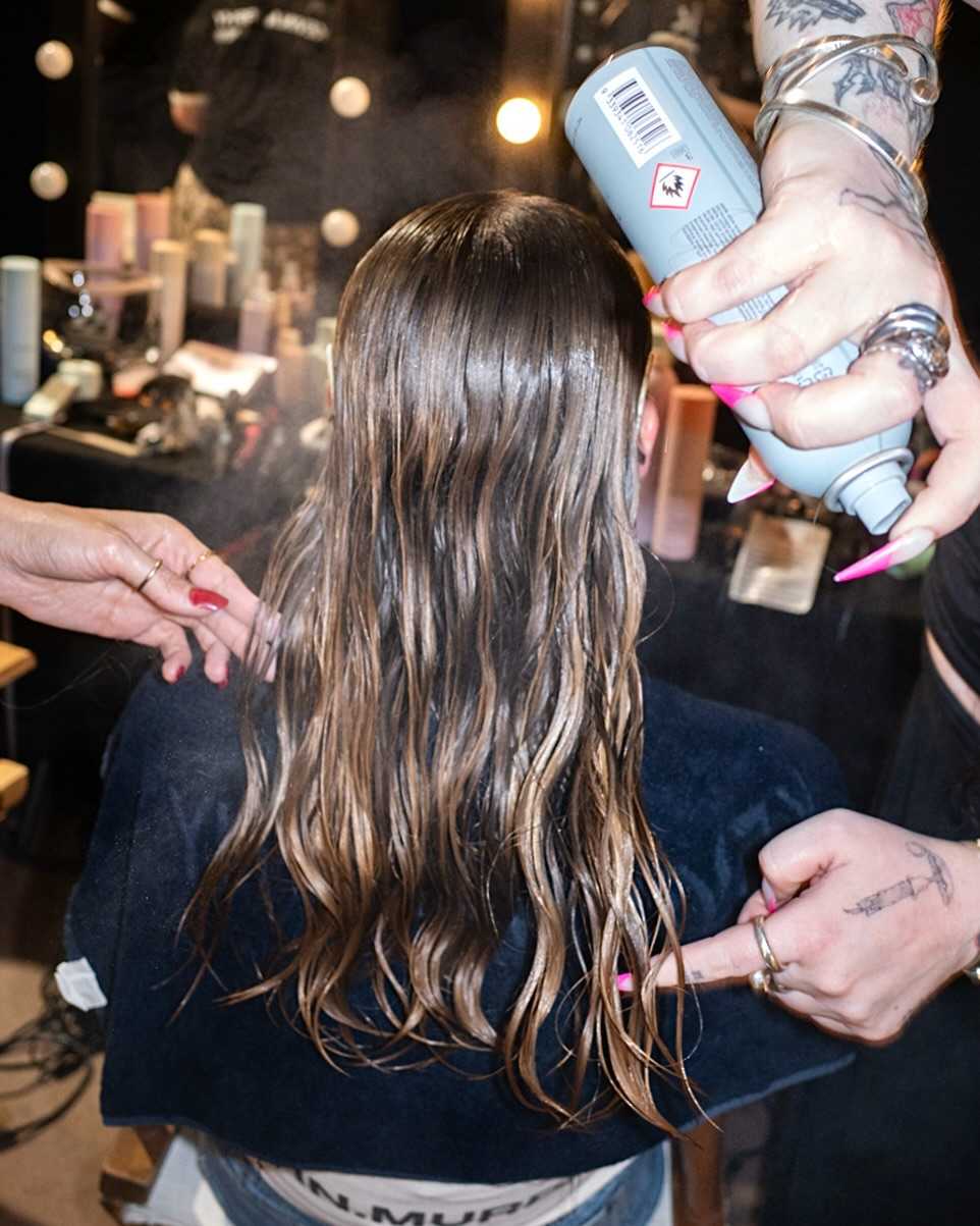 Hairstylist applying KEVIN.MURPHY styling products backstage during a professional hair styling session.