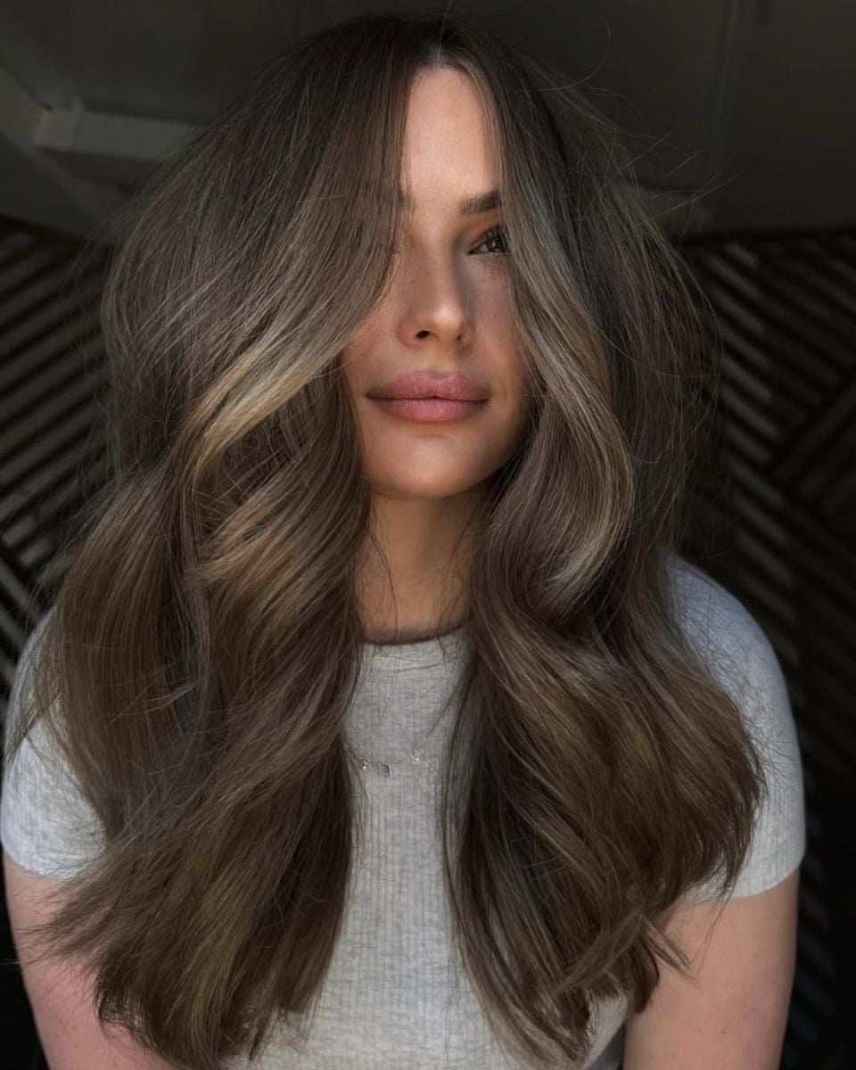 Front view of long lived-in bronde hair with a shadow root, neutral beige highlights and soft voluminous waves.