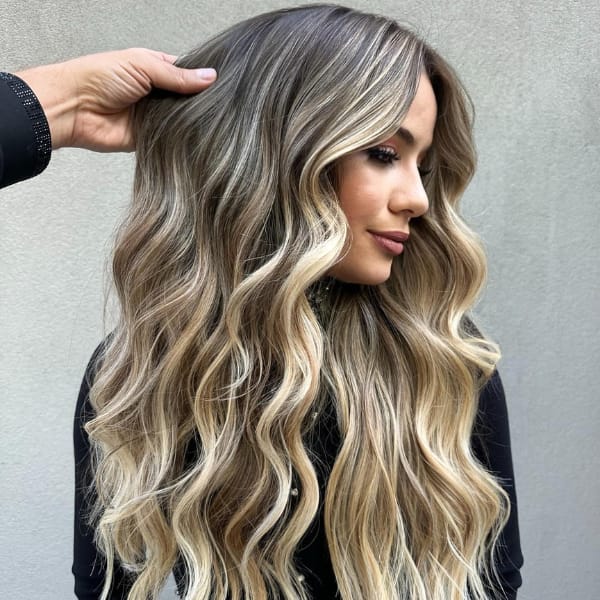 Long wavy blonde balayage hairstyle with soft highlights, styled by Gabriel Samra, showcasing natural beachy waves and multi-dimensional color.