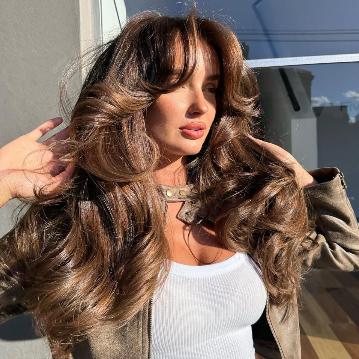 model with voluminous layers and a no bleach balayage outside in the sun