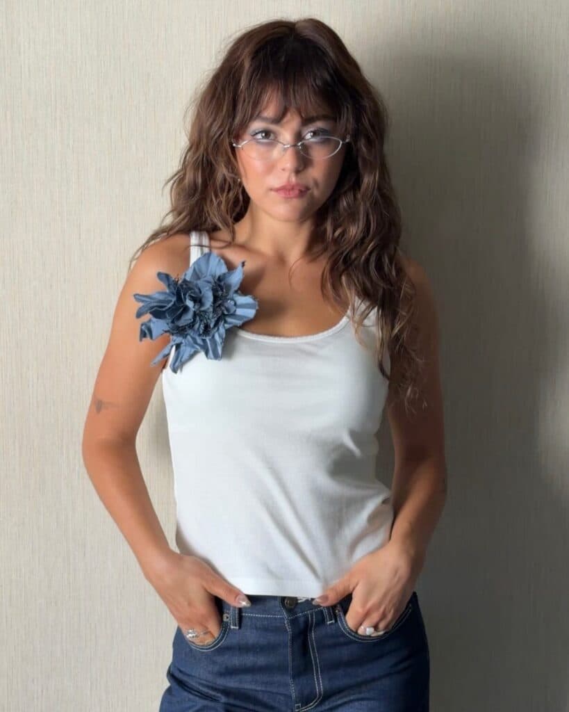 Mika Abdalla wearing Allie Hayes' signature shag haircut with textured layers and full bangs during the Off Campus press tour.