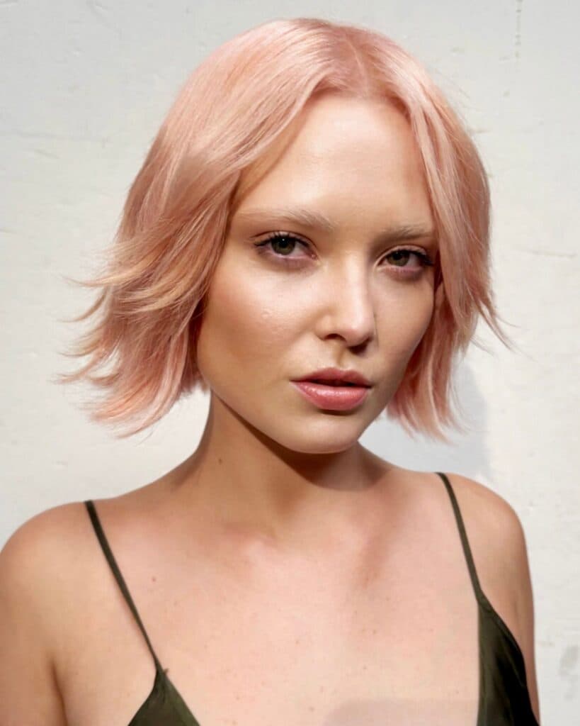 Luminous pastel pink bob with soft texture and shine, featuring a delicate blush-pink tone on a short layered haircut.