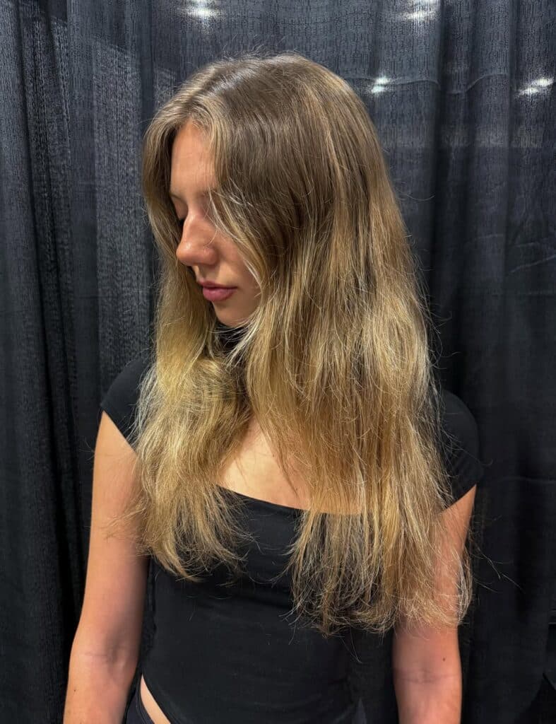 Long natural dark blonde hair with grown-out color, subtle lighter ends, minimal dimension and a straight, unstyled finish.