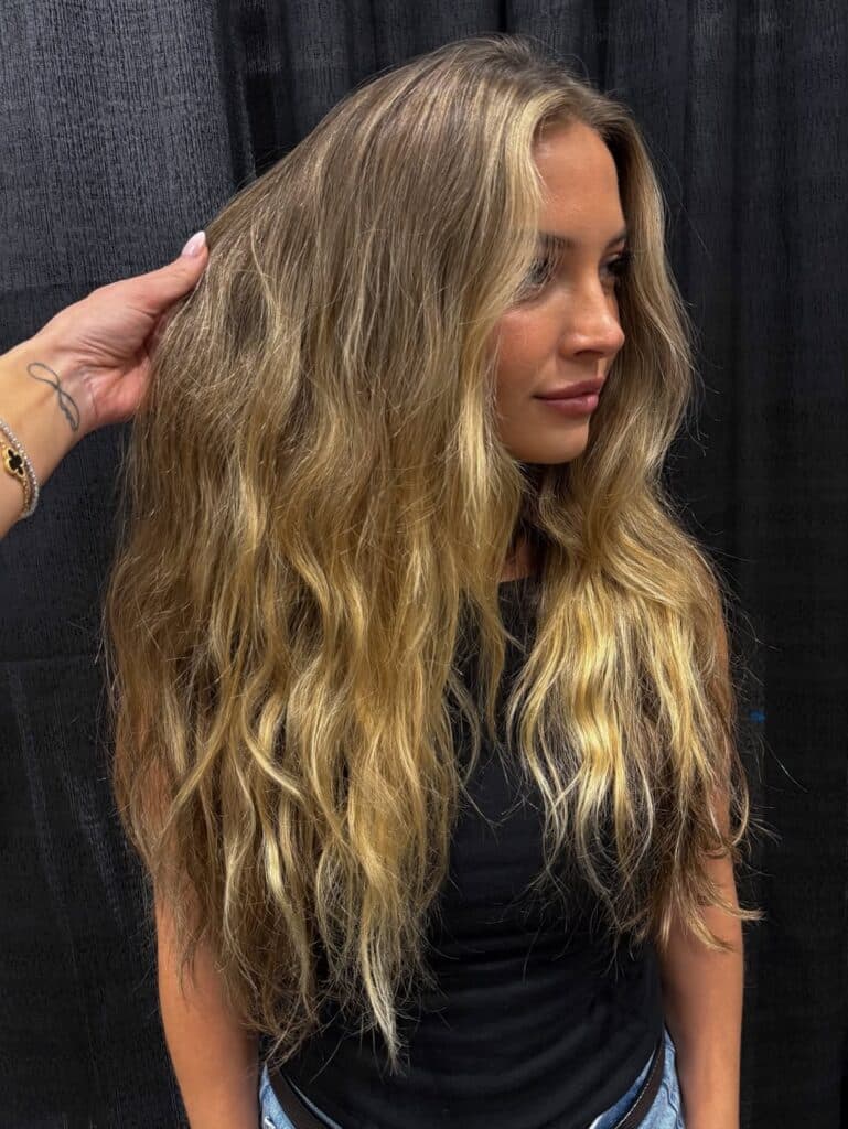 Long natural dark blonde hair with grown-out color, subtle lighter ends, minimal dimension and a straight, unstyled finish.