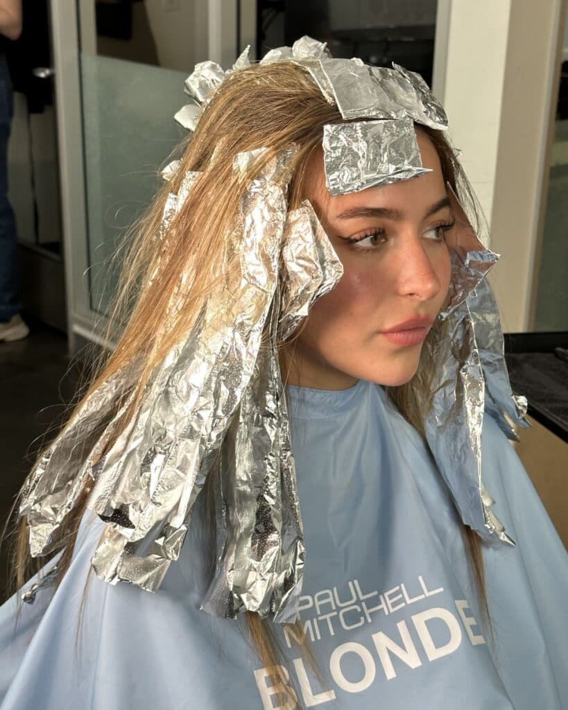 Foil placement begins with fine weaves throughout the hairline and top sections to create bright, sun-kissed ribbons of blonde.