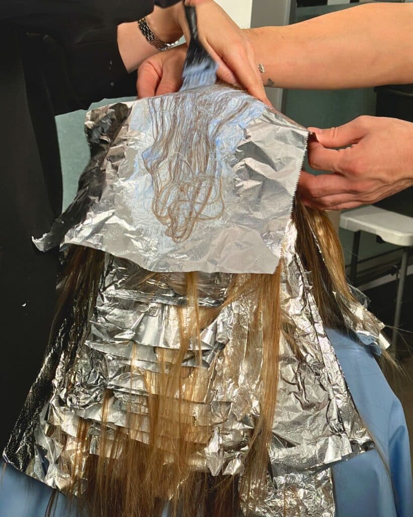 Foils are layered through the back and crown using a high-density highlighting pattern for seamless blonde dimension from roots to ends.