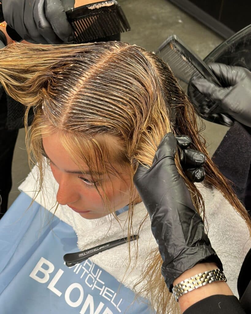 A root smudge is applied after blonding to soften regrowth, add depth and blend the highlighted ribbons into the natural base.